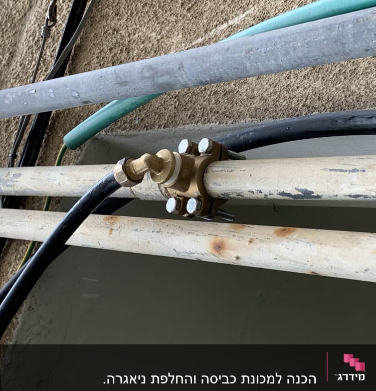 צינורות מתכת עם חיבורי ברזים על קיר
